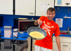 One student flipping eggs